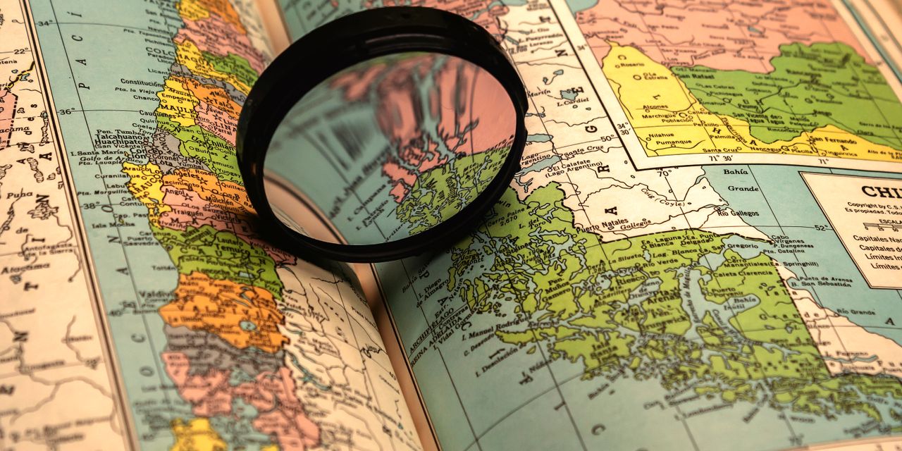 A close-up of a colorful world map with a magnifying glass highlighting details.