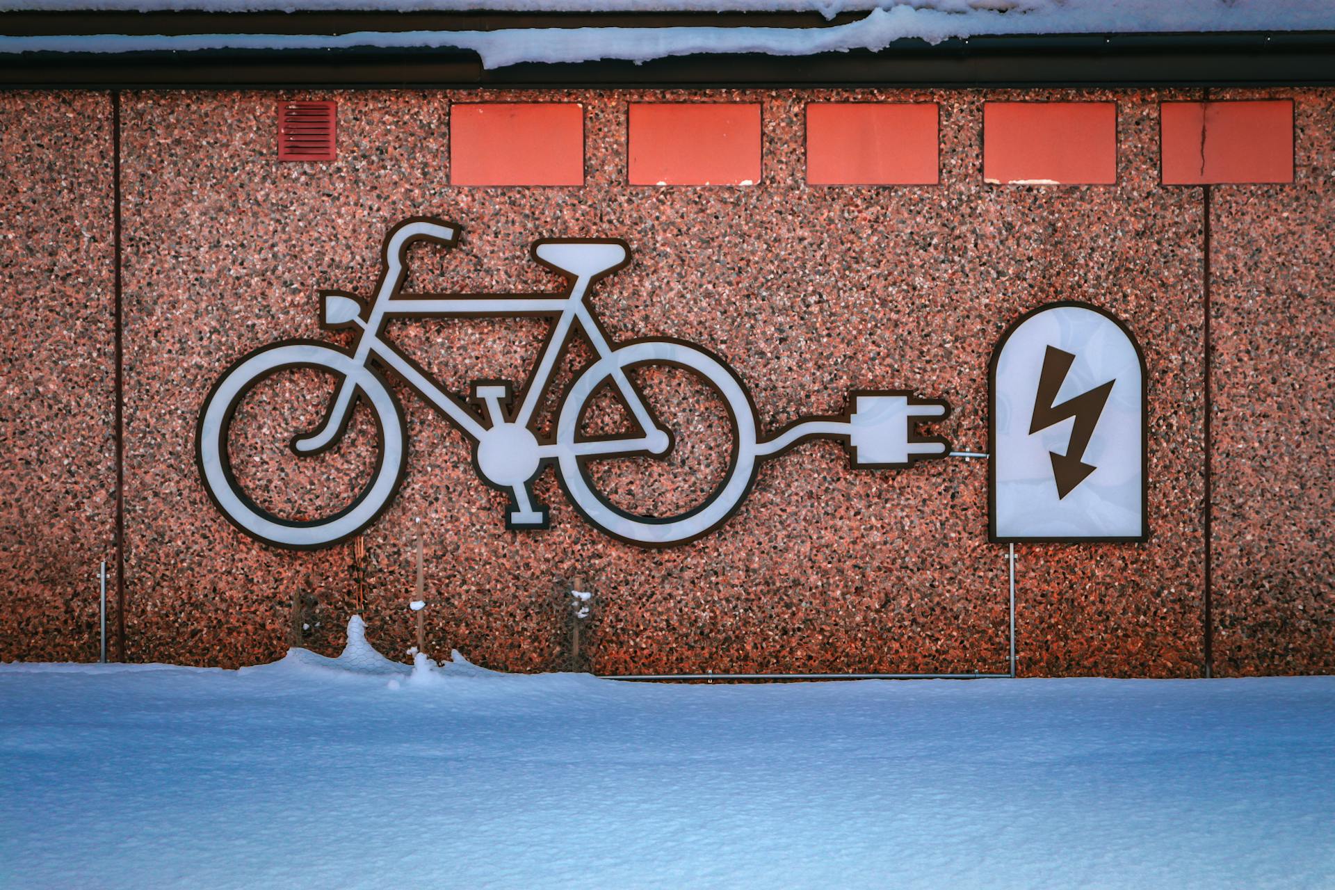 Electric bike charging graphic on a snowy urban wall, promoting renewable energy.
