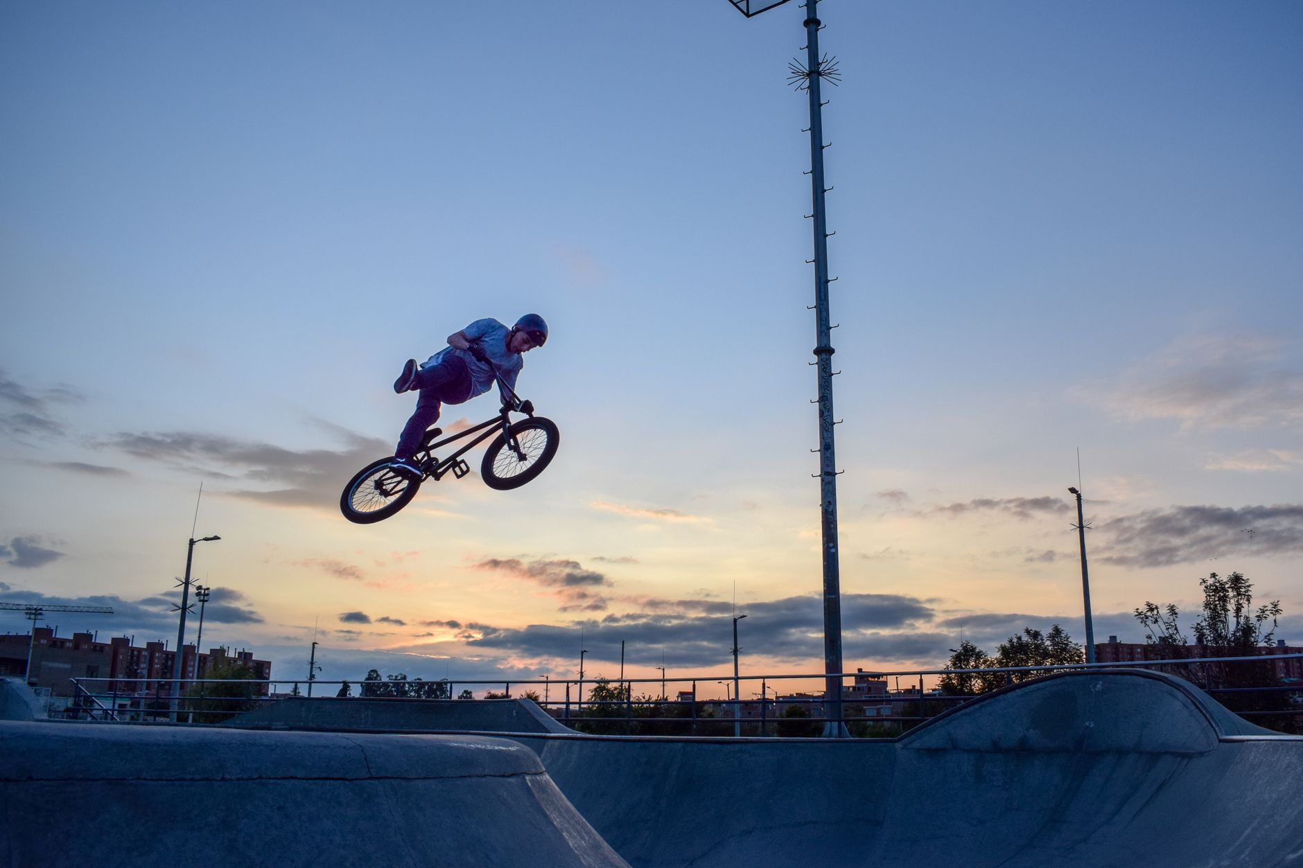 Houston skatepark at dusk, rider carving a concrete bowl while vintage deck graphics catch fading light