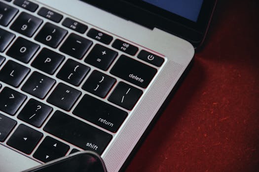 Detailed shot of a laptop keyboard highlighting black keys and a red background.