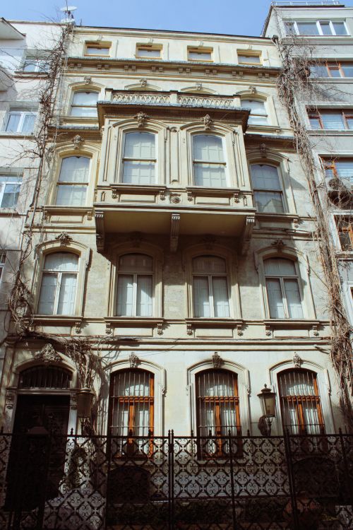 Free A low-angle shot of a historical building facade showcasing intricate architectural details and vertical design. Stock Photo