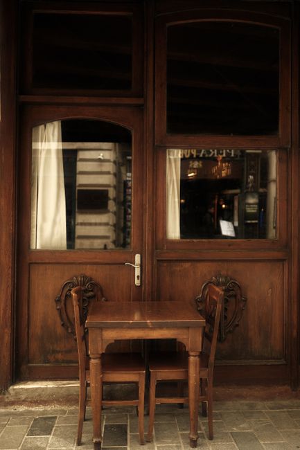 Vintage-style wooden table and chairs set against a classic café backdrop perfect for cozy scenes.