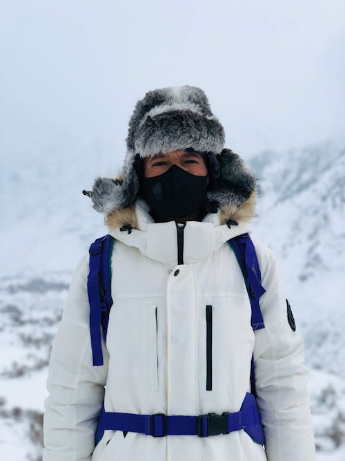 Person in White Jacket and Fur Hat in Snowy Mountains