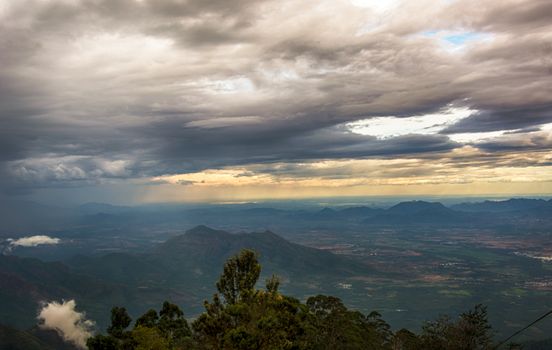 Dramatic cloudy sky over a mountain range during sunset, showcasing nature's beauty.
