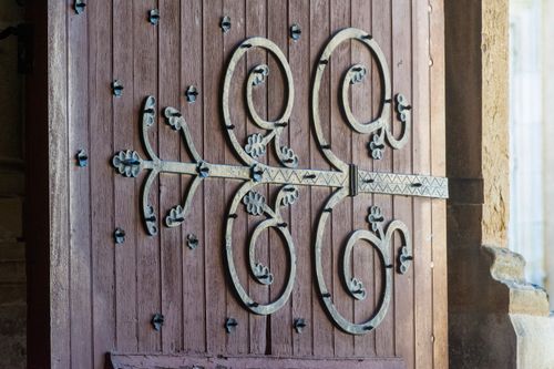 Free Close-up of detailed wrought iron decor on a rustic wooden door showcasing craftsmanship. Stock Photo
