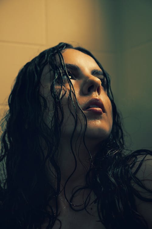 Young Woman with Her Hair Standing in the Shower and Looking Up 