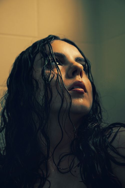 Free A young woman with wet brunette hair looks contemplatively upwards in a shower. Stock Photo