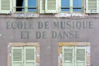 Facade of a French music and dance school with classic shutters and signage.