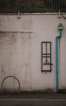 A textured urban wall in Dublin, featuring a rusty fixture and blue piping, capturing city decay.