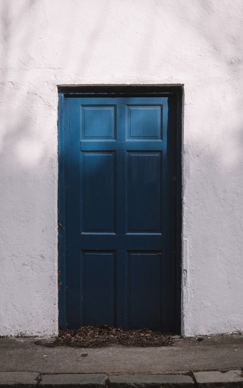 Free A traditional blue door on a white wall in Dublin, Ireland, in a minimalist style. Stock Photo