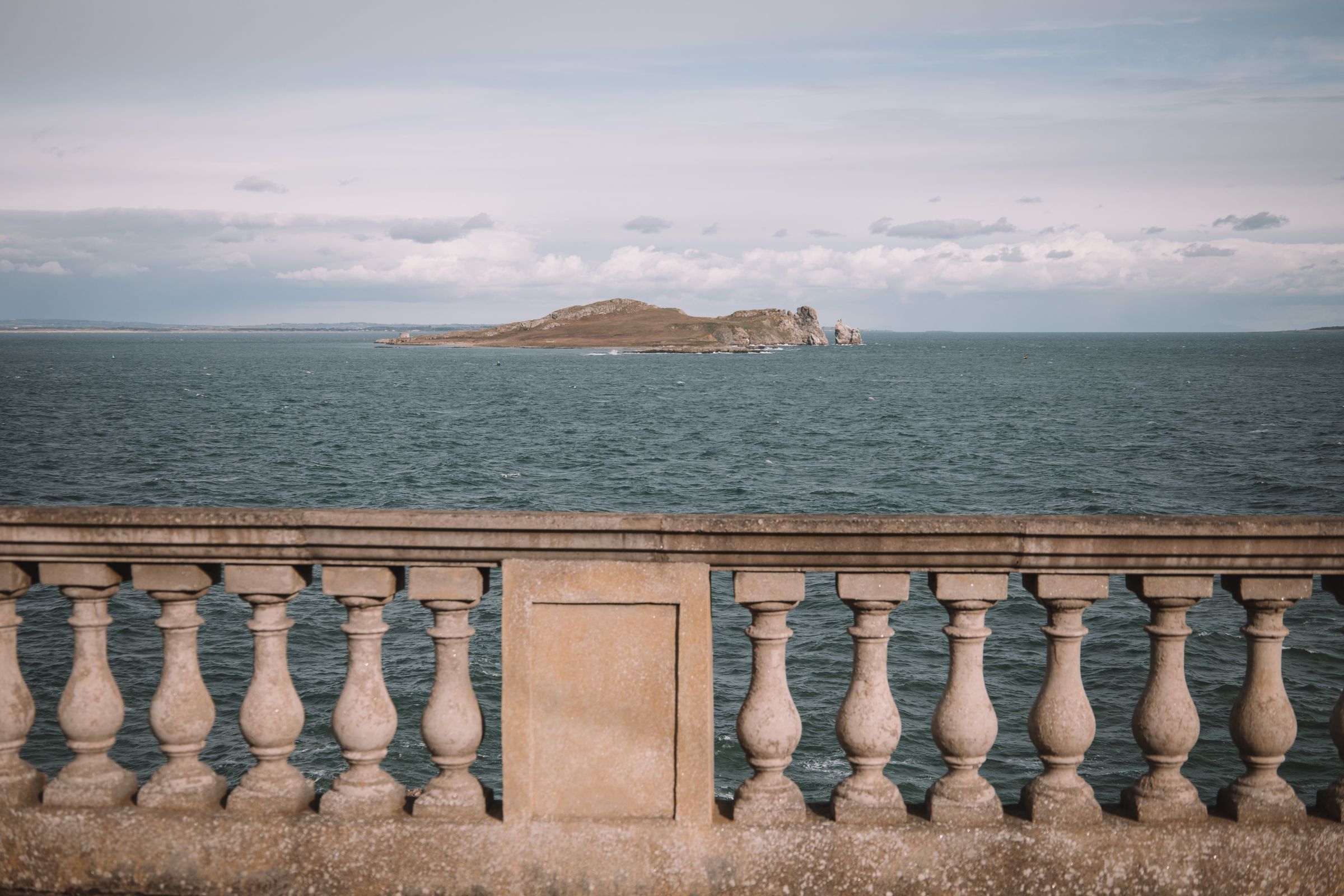 Seascape featuring Dublin Bay and a classic stone railing under a cloudy sky