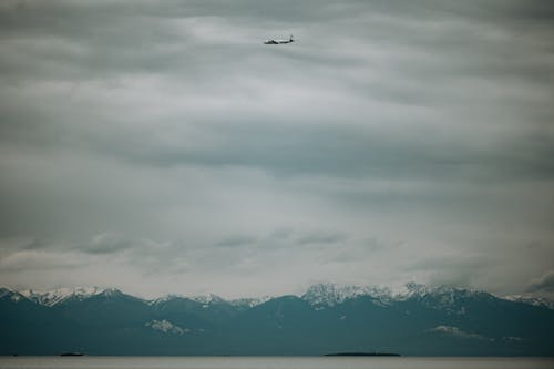 Airplane Flying above Mountains and Water