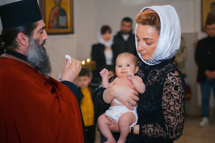 Priest Christening Newborn Baby In Church