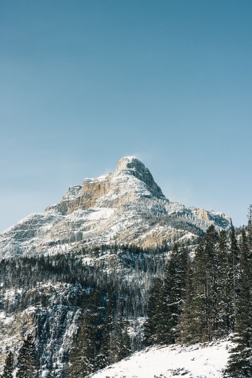 Free Majestic snowcapped peak in Kananaskis, Alberta, surrounded by forested slopes. The essence of Canadian wilderness. Stock Photo