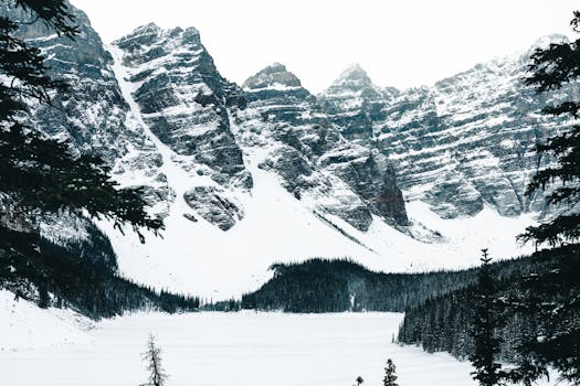 Snowy mountain peaks and frozen lake in Banff National Park create a serene winter landscape.