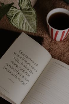 Open journal with inspirational quote, coffee, and plant on carpet, perfect for creative motivation.