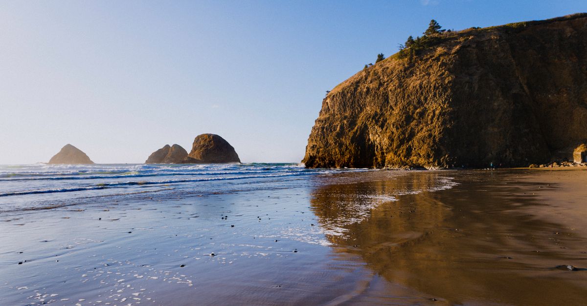 Beautiful Oregon coast with cliffs and sea stacks under a clear blue sky.