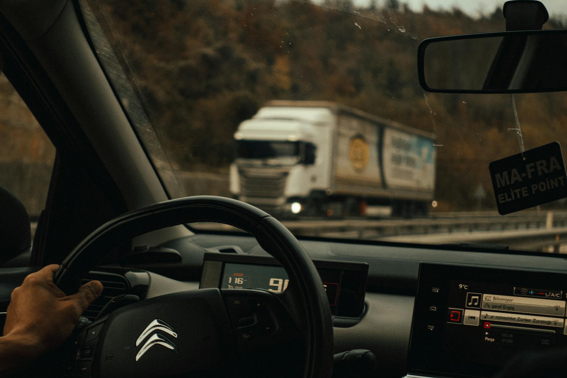 Interior view of a car driving on the highway with a truck visible ahead.