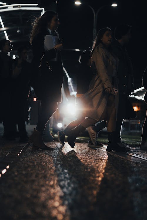 View of Pedestrians Crossing the Street at Night with Car Headlights Glowing in the Background