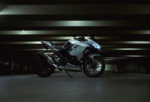 Free White Kawasaki motorcycle parked in a dark parking garage, showcasing modern design and sleek lines. Stock Photo