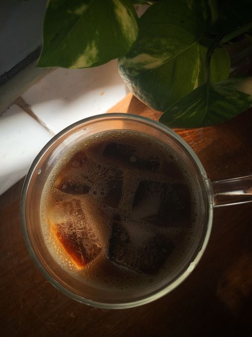 Free Top-view of iced coffee in glass with ice cubes and green leaves, perfect for summer vibes. Stock Photo