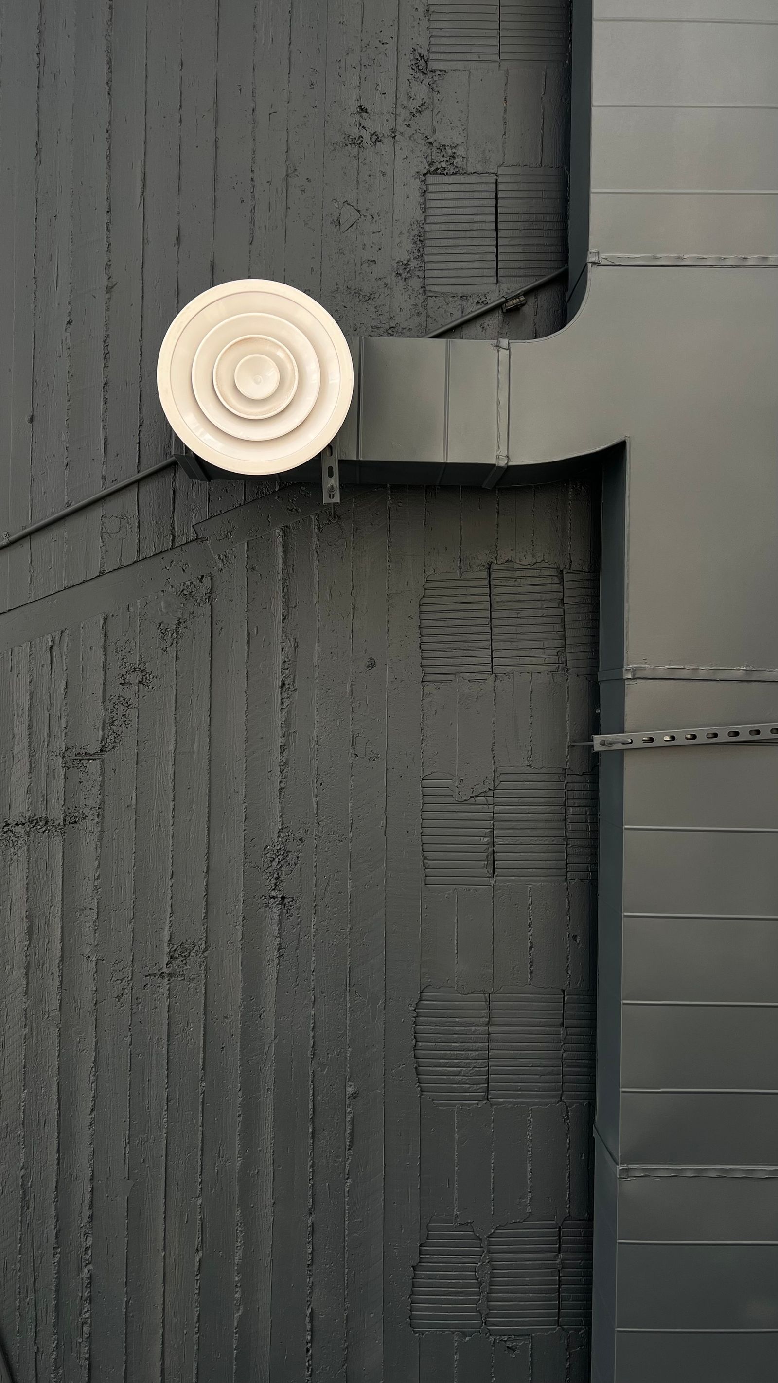 TAB service areas — close-up of a circular supply diffuser on a modern commercial building facade