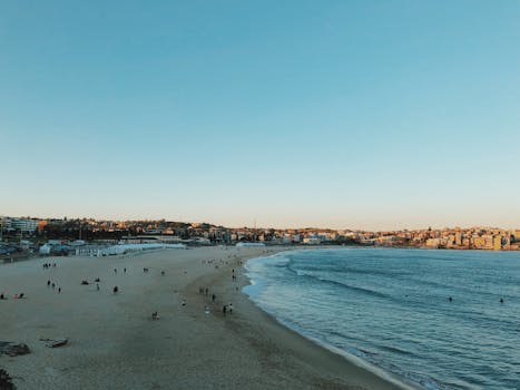 A scenic view of Bondi Beach with people enjoying the sunset along the sandy shore.