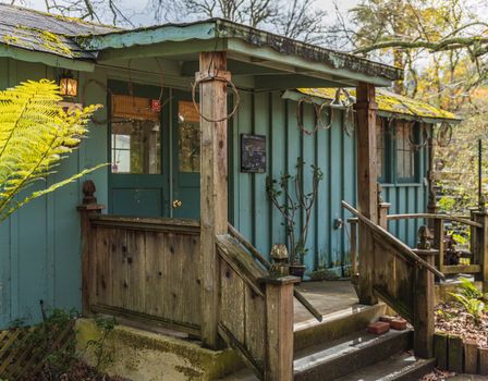 A rustic bungalow with a wooden porch and lush greenery, perfect for serene living.