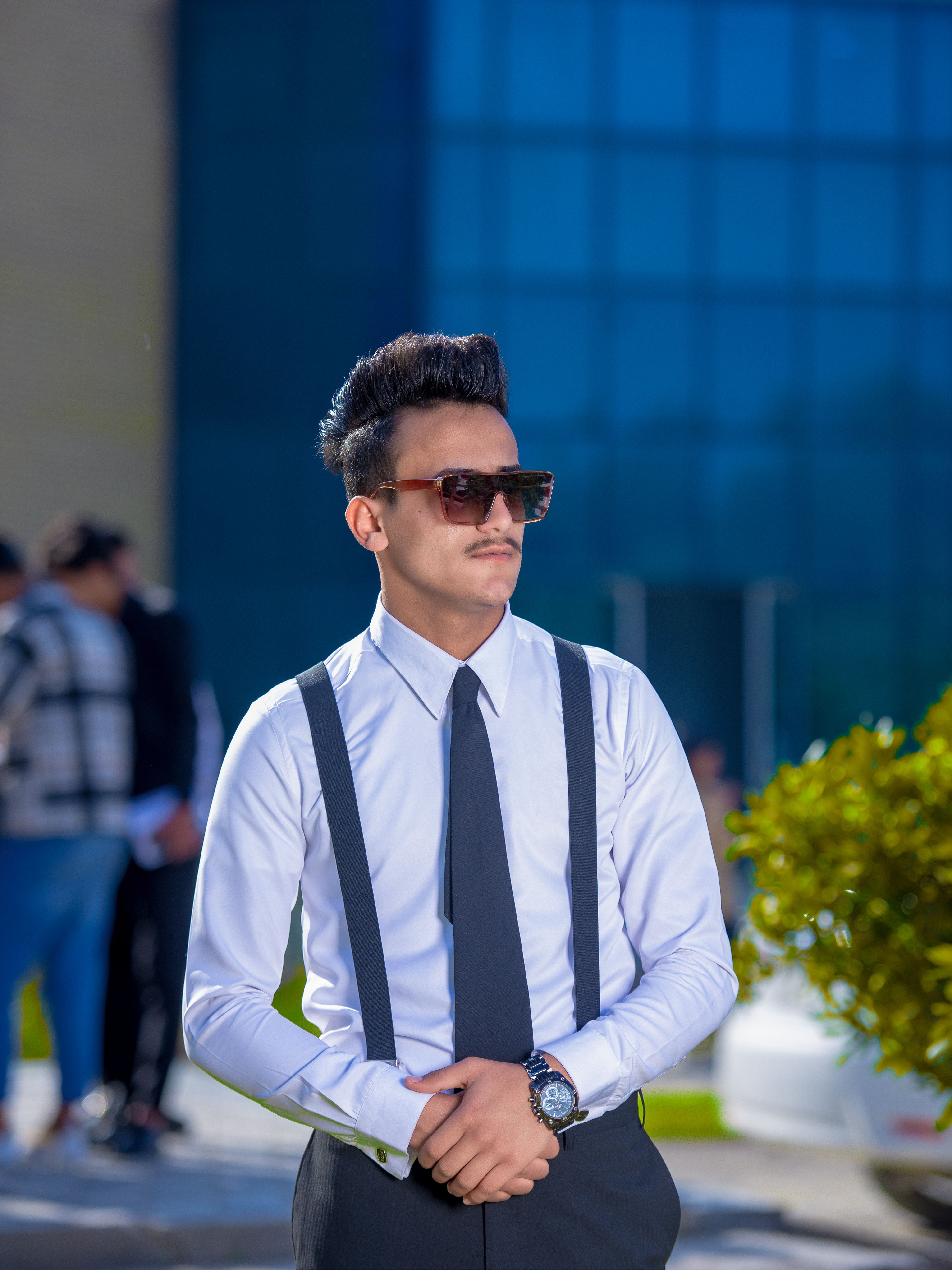 Portrait of a stylish young man in formal attire and sunglasses outdoors. Modern fashion photography.