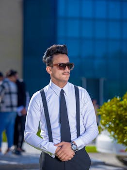 Portrait of a stylish young man in formal attire and sunglasses outdoors. Modern fashion photography.