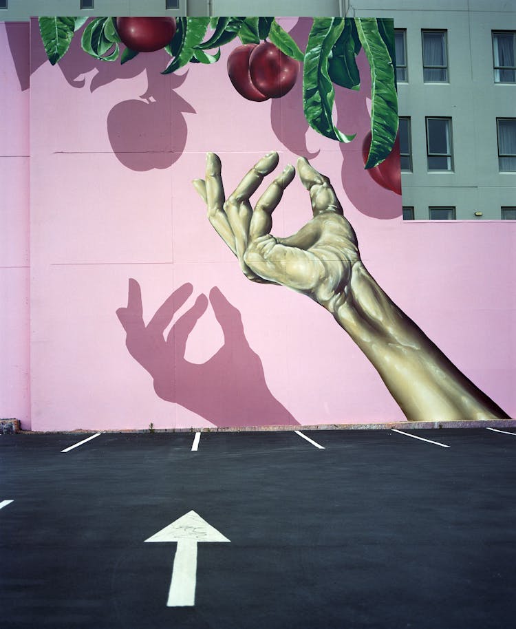 A Mural Of A Hand Reaching For An Apple Painted On A Wall In City 