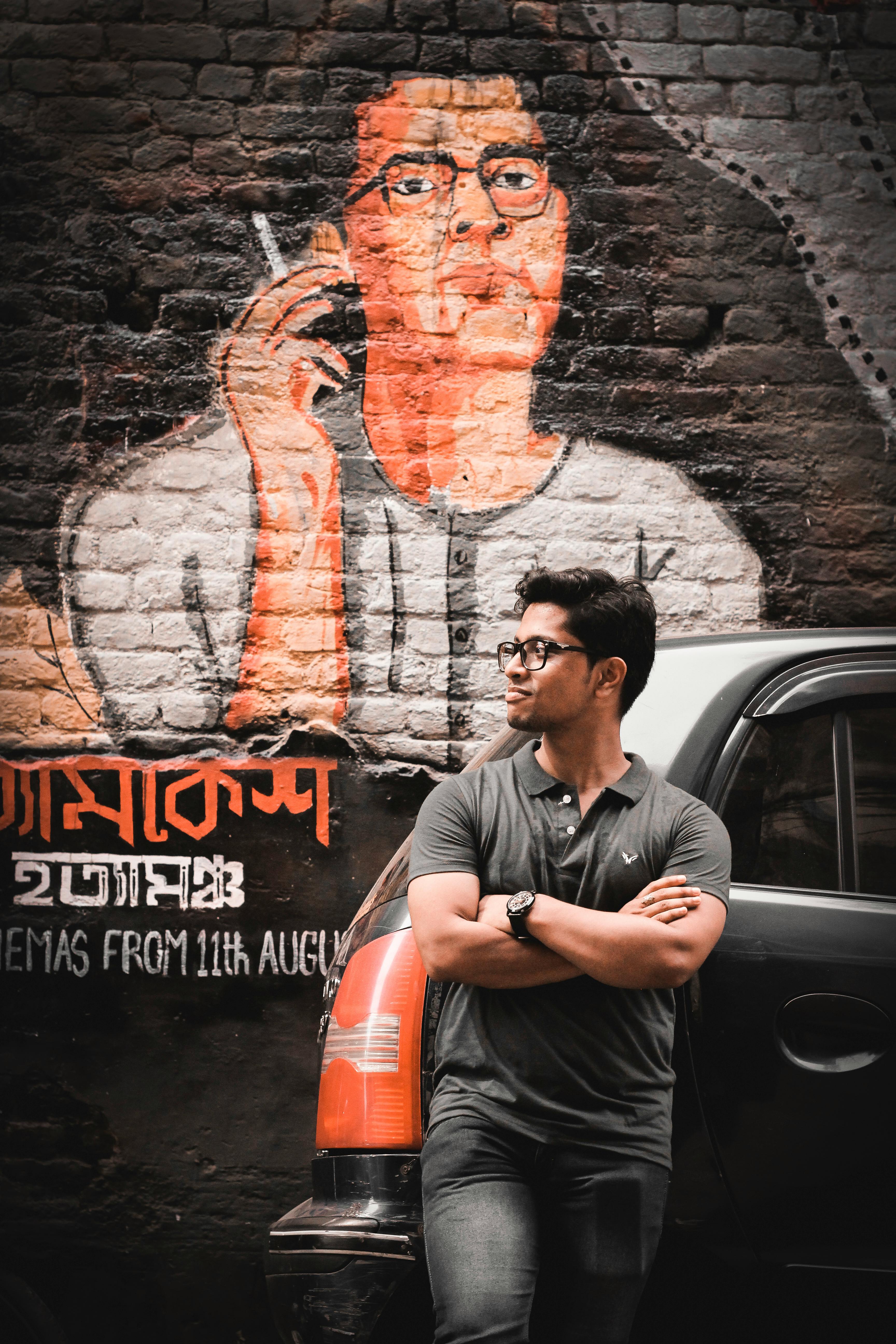Portrait of a man standing beside vibrant graffiti art in Kolkata, India, reflecting urban culture.