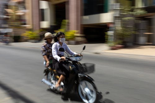 Two Women Riding on a Scooter on a City Street 