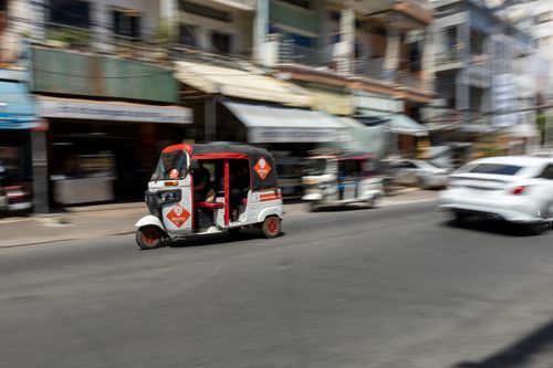 Free Dynamic urban scene capturing a speeding auto rickshaw on a bustling city street. Stock Photo