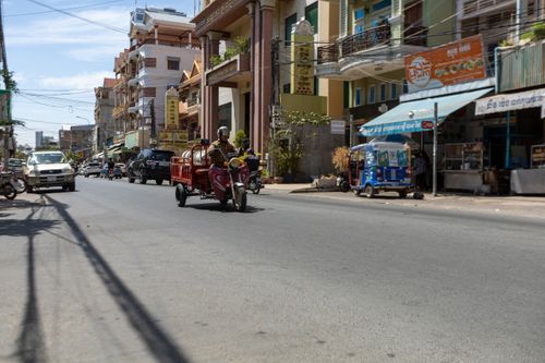 Free Busy Southeast Asian street with motorbike and colorful buildings on a sunny day. Stock Photo