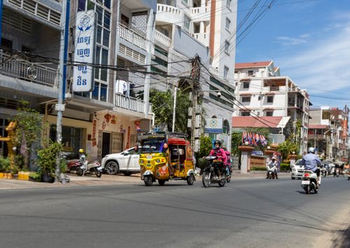 Free Vibrant street in Phnom Penh showcasing tuk-tuks, scooters, and bustling city life. Stock Photo