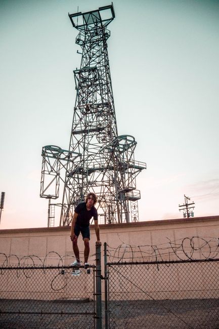 Advanced Microsoft 365 Security Strategies 5 - Microsoft 365 Security Strategies,Advanced Microsoft 365 Security Strategies For Architecture And Energy Firms - - Bonelli Systems A Man Climbing Over A Barbed Wire Fence Near A Large Transmission Tower At Dusk.