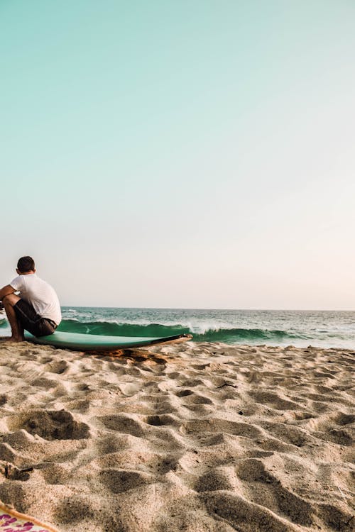 Zdjęcie Mężczyzny Siedzącego Na Desce Surfingowej
