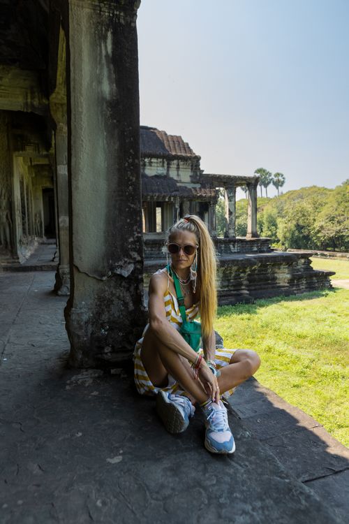 Free Tourist woman with sunglasses sitting at Angkor Wat, Cambodia, enjoying a sunny day. Stock Photo
