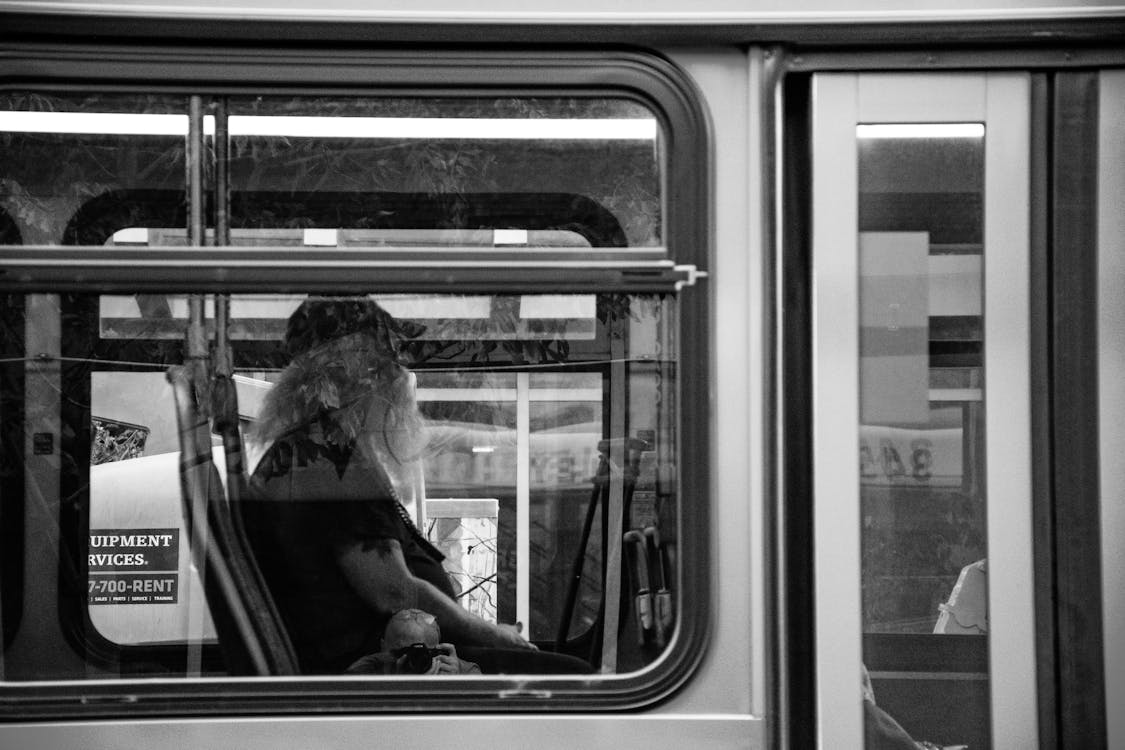 Grayscale Photography of Man Sitting Inside Bus