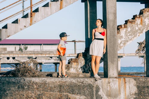 Woman Beside Girl Under Concrete Bridge
