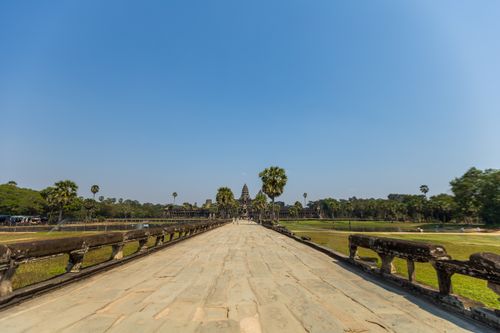 Free Explore the majestic pathway leading to the historic Angkor Wat temple under a clear blue sky. Stock Photo