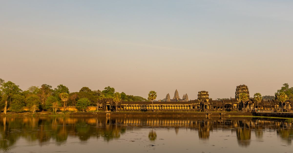 The towers of Angkor Wat reflected in the pond in front of the temple at sunrise, Cambodia