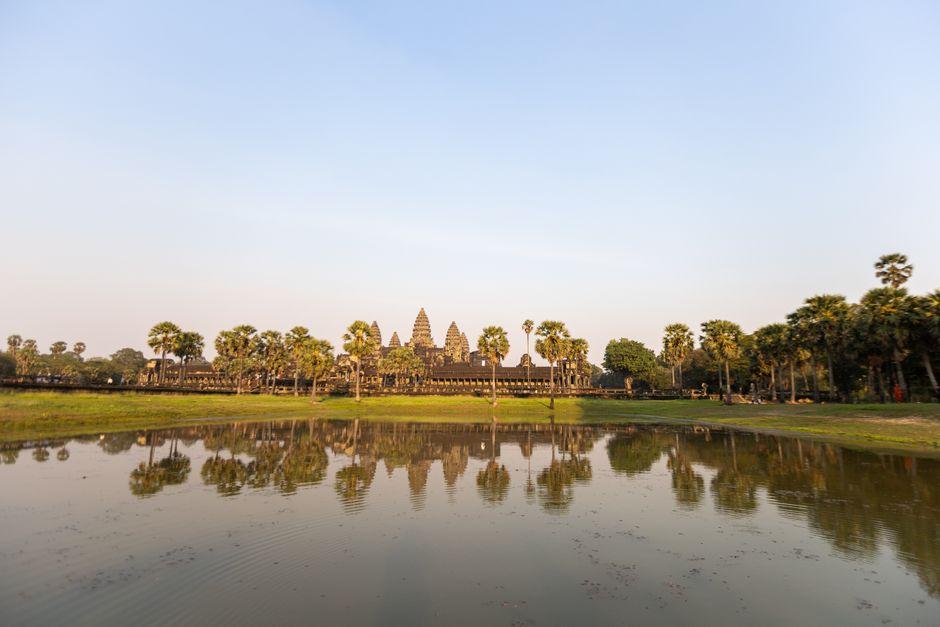 Temple Angkor Wat reflété dans un bassin au lever du soleil avec palmiers, Cambodge