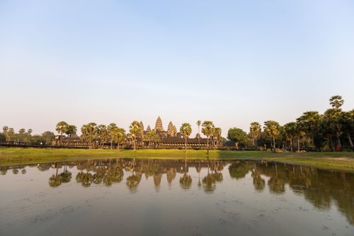 Free Stunning sunrise over Angkor Wat temple with reflective water and palm trees. Stock Photo