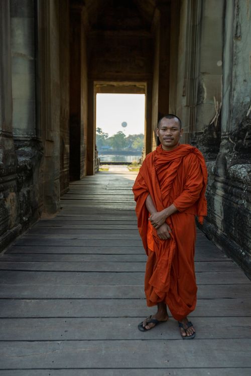 Free A serene Buddhist monk in traditional robe stands in an ancient temple corridor. Stock Photo