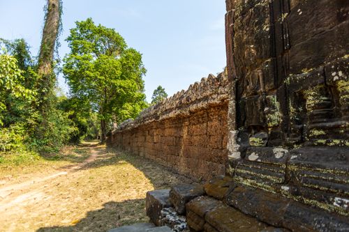 Free A weathered temple wall amidst lush greenery in Cambodia, showcasing historical architecture. Stock Photo