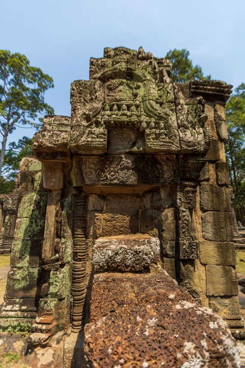 Free Sunlit ancient stone ruins with intricate carvings, surrounded by nature under a clear blue sky. Stock Photo