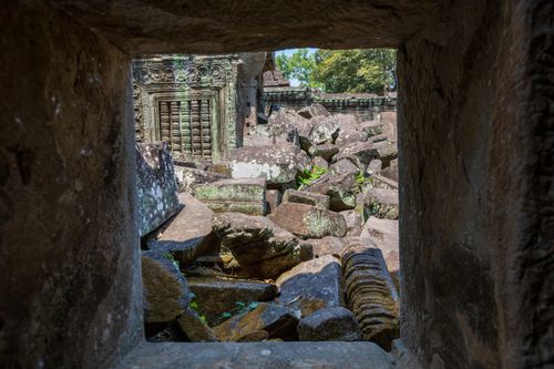 Free A glimpse through an ancient window reveals the Angkor Wat ruins. Stock Photo