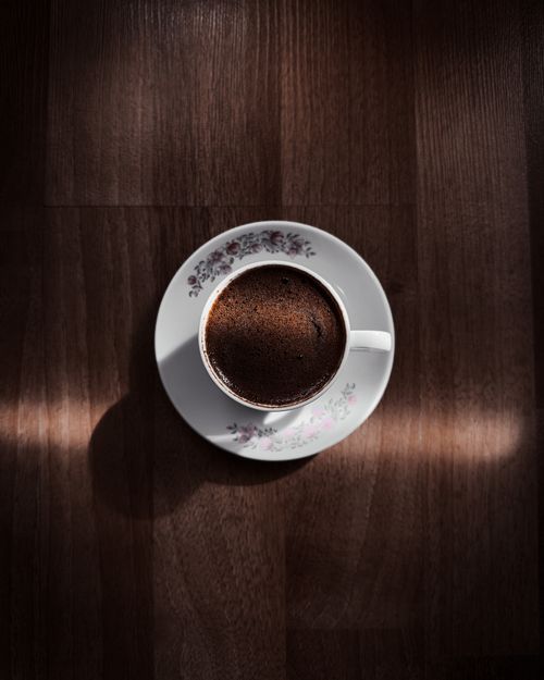 Free Aerial view of a coffee cup casting soft shadows on a wooden table. Stock Photo